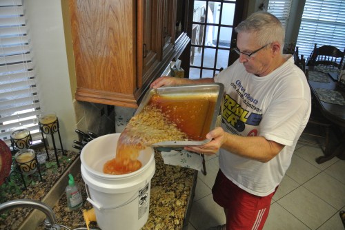 Pouring off  the honey and wax bits into the pail. There is a fine sieve screen that sits on the top of the pail to catch the small stuff.